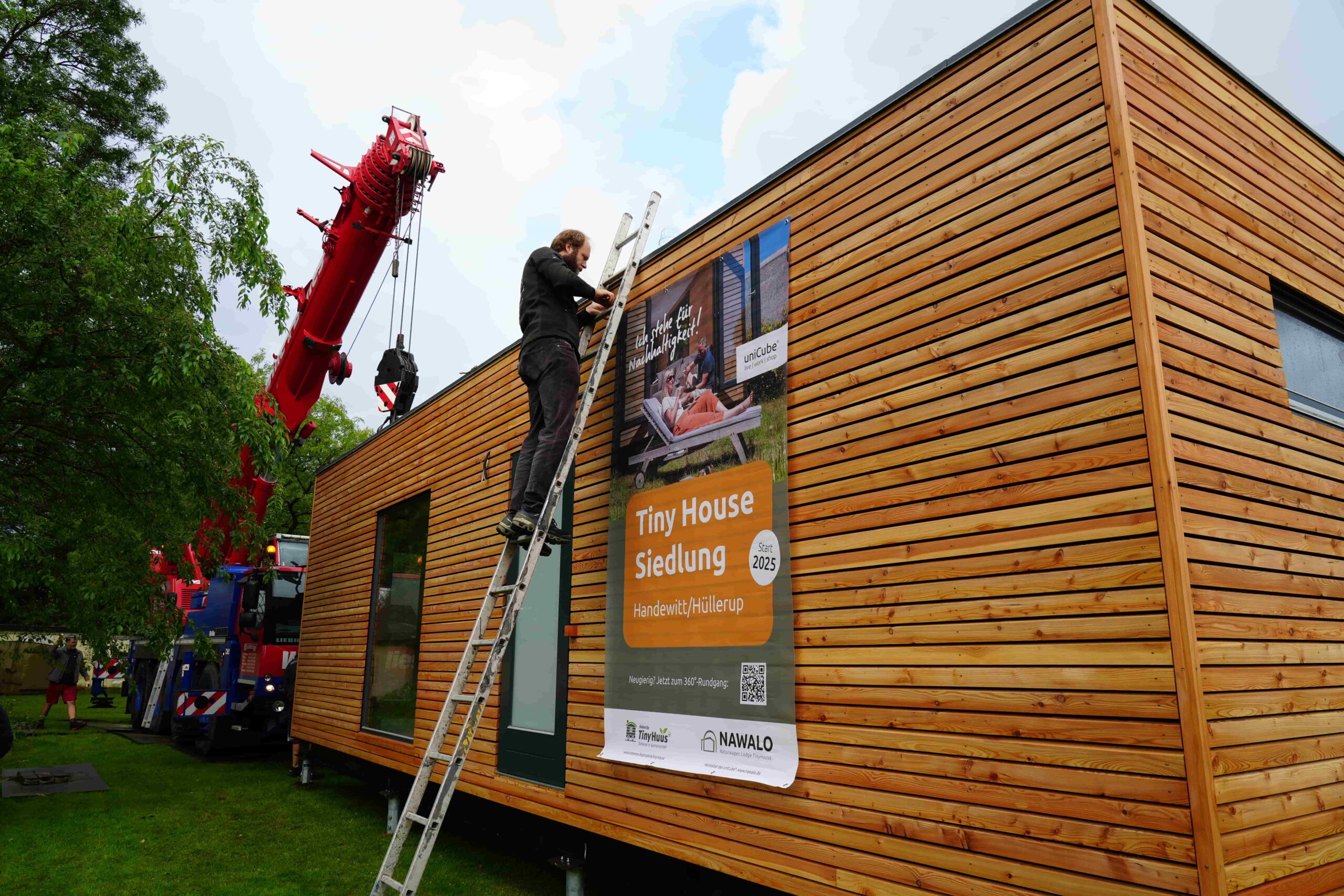Ein Mann auf einer Leiter an einem Tiny House