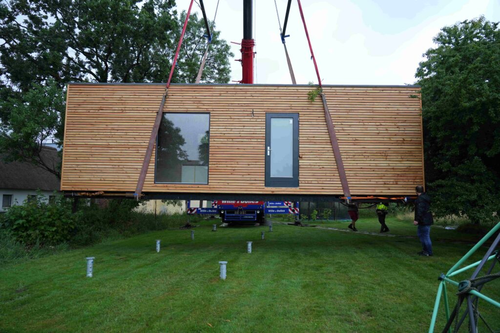 Ein Tiny House, das von einem Kran auf ein Fundament herunter gelassen wird